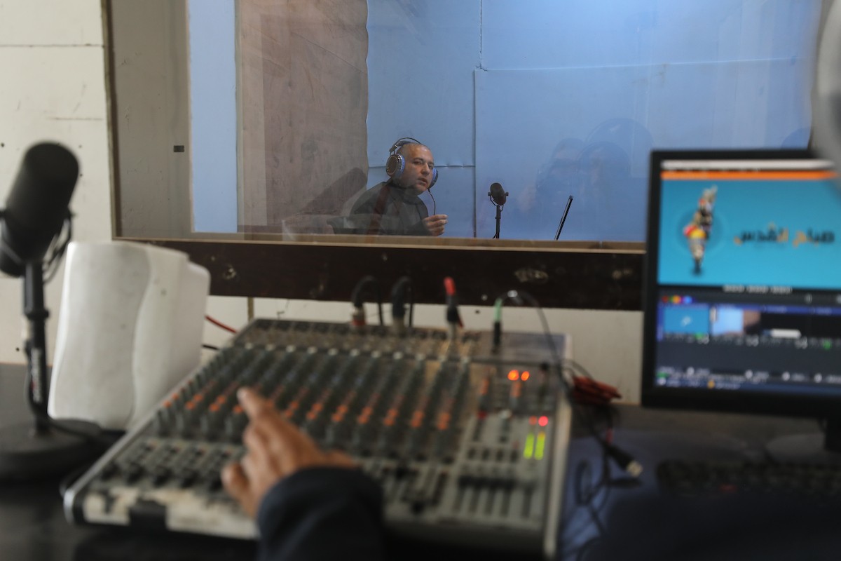 مذيع راديو فلسطيني يبث عبر الإنترنت من استوديوهات إذاعة صوت القدس في غزة، 24 يناير/كانون الثاني 2026. عادت الإذاعة إلى البث بعد توقف دام عامين بسبب الحرب، معتمدةً على معدات بسيطة للتواصل مع الجمهور المحلي ونقل الأخبار عن الأوضاع الإنسانية في القطاع. صورة: عمر أشتوي
