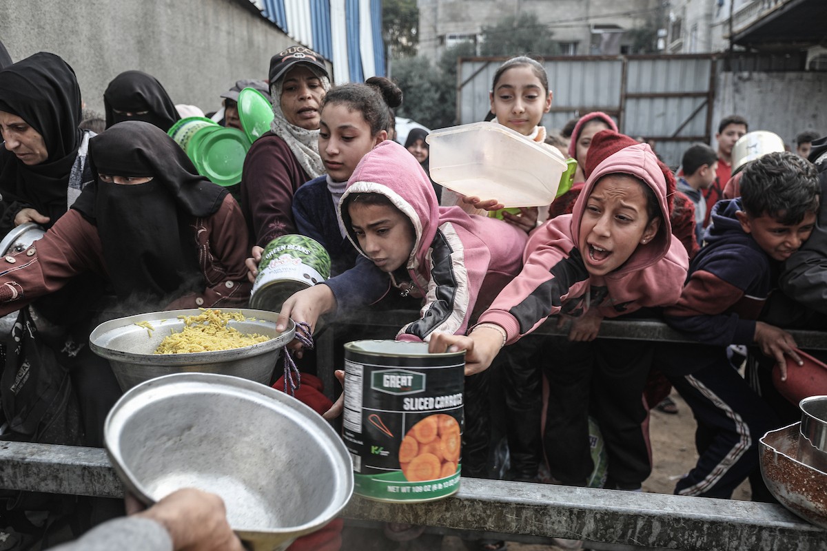أطفال فلسطينيون ينتظرون وجبة ساخنة، توزعها إحدى المنظمات الخيرية، في ظل استمرار أزمة الغذاء بسبب محدودية المساعدات الإنسانية في مخيم النصيرات للاجئين وسط قطاع غزة، في 10 يناير/كانون الثاني 2026. صورة: معز صالحي