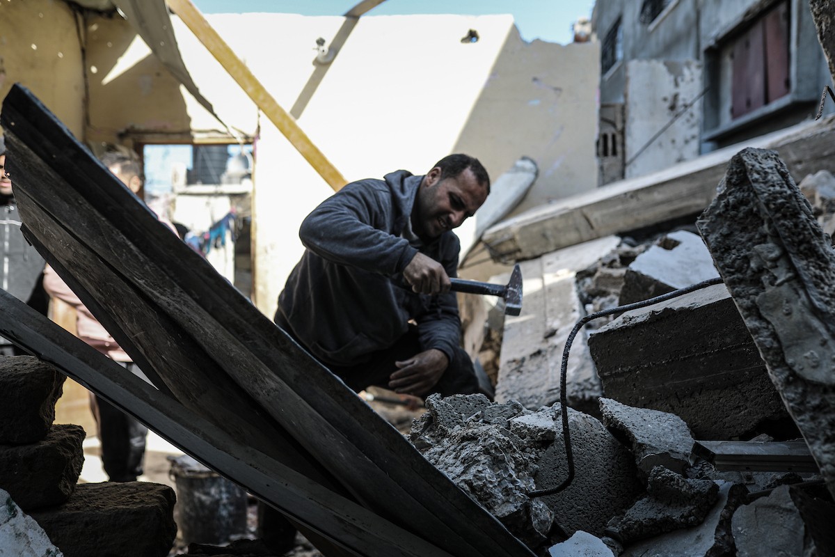 فلسطينيون يتفقدون منزلاً (تضرر سابقاً جراء غارة جوية إسرائيلية) انهار على سكانه، ما أسفر عن وفاة رجل ونجله الصغير في مخيم المغازي للاجئين وسط قطاع غزة، 5 يناير/كانون الثاني 2026. صورة: رمزي أبو عامر