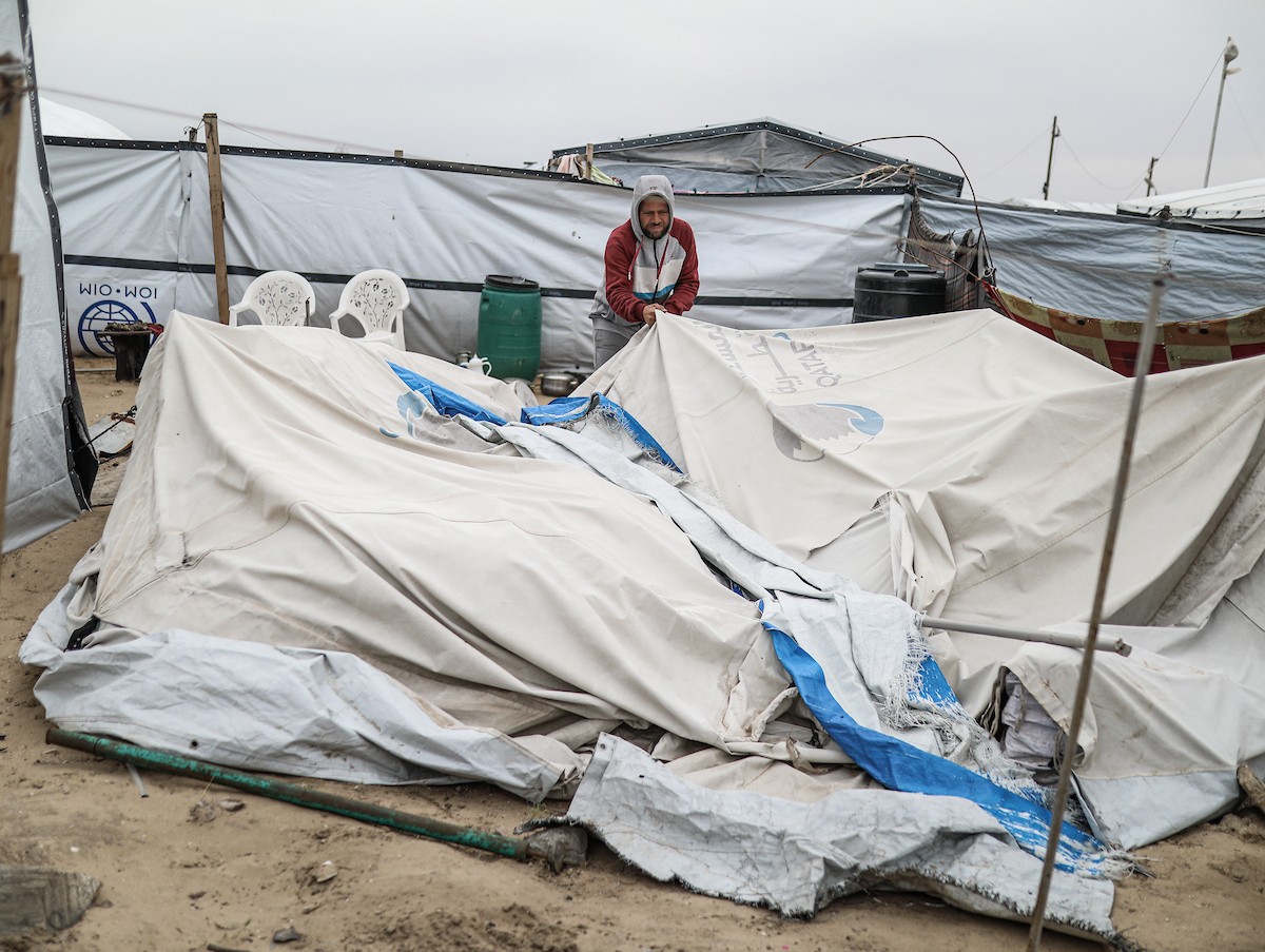 يتفقد فلسطينيون نازحون خيامهم بعد أن تضررت بشدة جراء عاصفة هوائية قوية ضربت مخيمًا للنازحين وسط قطاع غزة. 22 يناير/كانون الثاني 2026. تصوير: رمزي أبو عامر