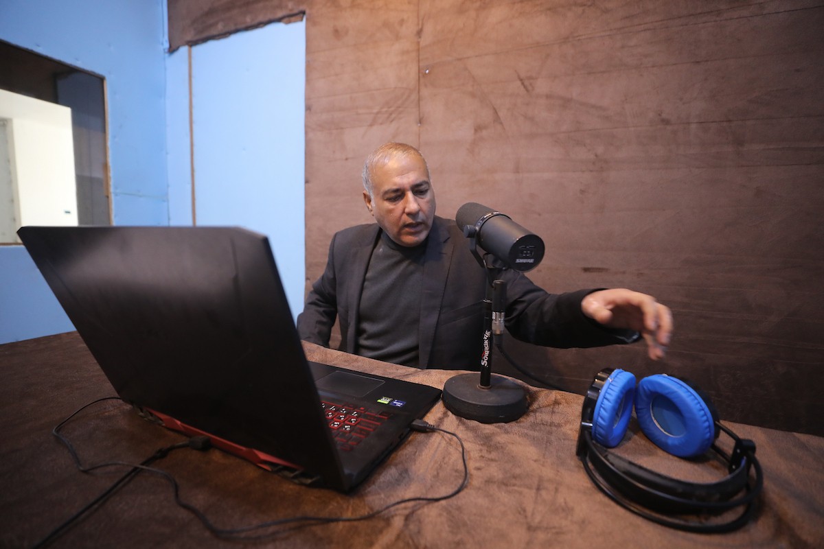 مذيع راديو فلسطيني يبث عبر الإنترنت من استوديوهات إذاعة صوت القدس في غزة، 24 يناير/كانون الثاني 2026. عادت الإذاعة إلى البث بعد توقف دام عامين بسبب الحرب، معتمدةً على معدات بسيطة للتواصل مع الجمهور المحلي ونقل الأخبار عن الأوضاع الإنسانية في القطاع. صورة: عمر أشتوي