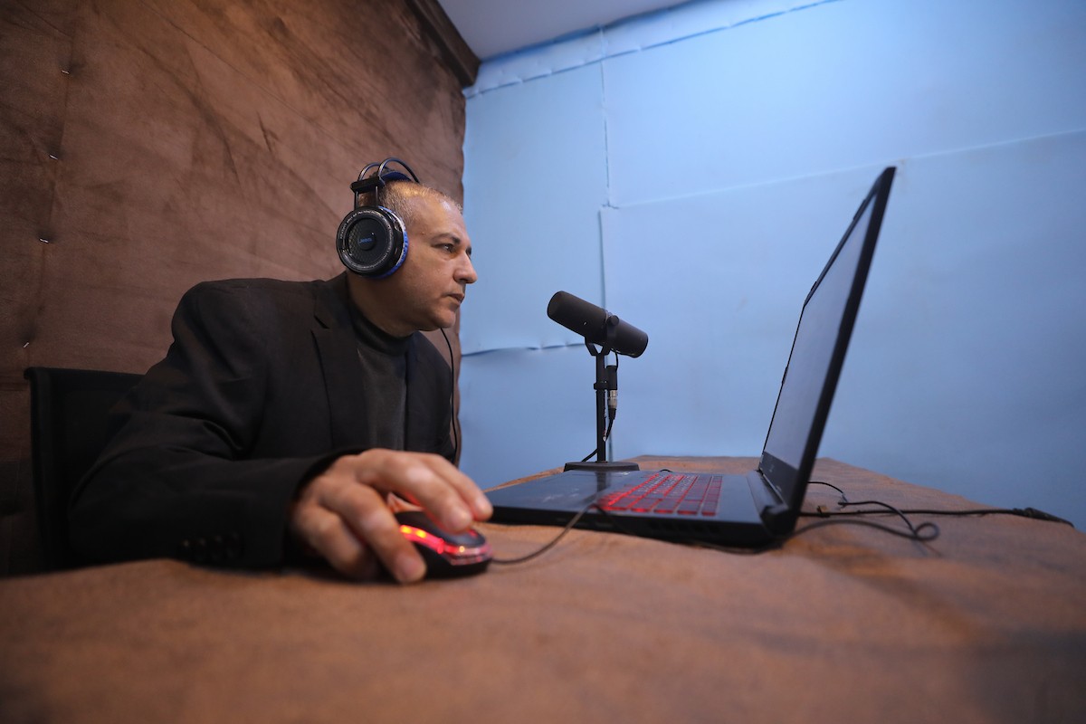 مذيع راديو فلسطيني يبث عبر الإنترنت من استوديوهات إذاعة صوت القدس في غزة، 24 يناير/كانون الثاني 2026. عادت الإذاعة إلى البث بعد توقف دام عامين بسبب الحرب، معتمدةً على معدات بسيطة للتواصل مع الجمهور المحلي ونقل الأخبار عن الأوضاع الإنسانية في القطاع. صورة: عمر أشتوي