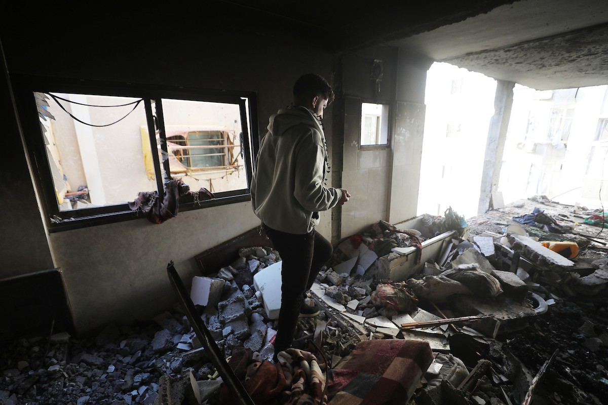 فلسطينيون يمرون أمام مبنى سكني تضرر جراء غارة عسكرية إسرائيلية أسفرت عن سقوط عدد من الضحايا في مدينة غزة، السبت 31 يناير/كانون الثاني 2026. صورة: عمر أشتوي