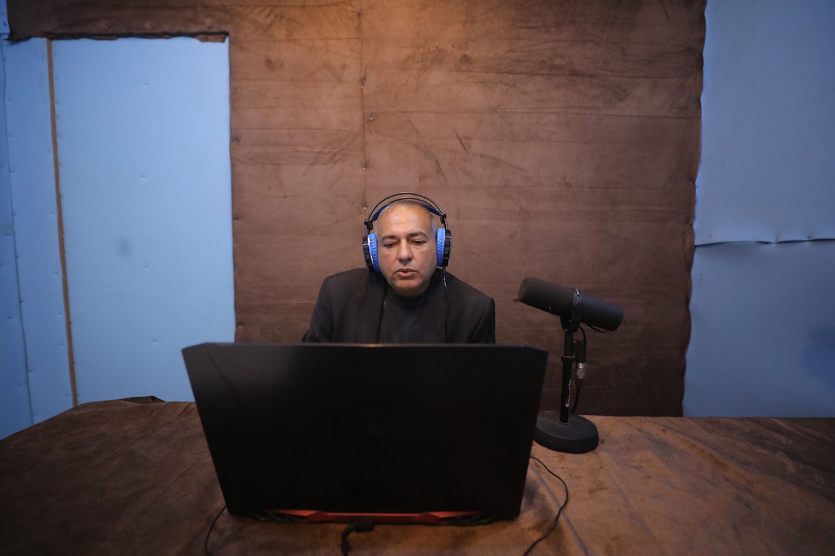 مذيع راديو فلسطيني يبث عبر الإنترنت من استوديوهات إذاعة صوت القدس في غزة، 24 يناير/كانون الثاني 2026. عادت الإذاعة إلى البث بعد توقف دام عامين بسبب الحرب، معتمدةً على معدات بسيطة للتواصل مع الجمهور المحلي ونقل الأخبار عن الأوضاع الإنسانية في القطاع. صورة: عمر أشتوي