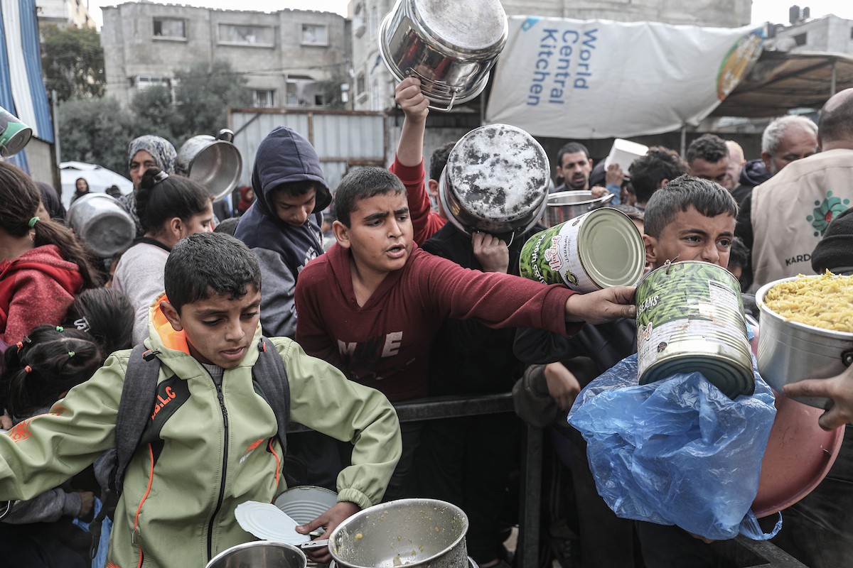 أطفال فلسطينيون ينتظرون وجبة ساخنة، توزعها إحدى المنظمات الخيرية، في ظل استمرار أزمة الغذاء بسبب محدودية المساعدات الإنسانية في مخيم النصيرات للاجئين وسط قطاع غزة، في 10 يناير/كانون الثاني 2026. صورة: معز صالحي