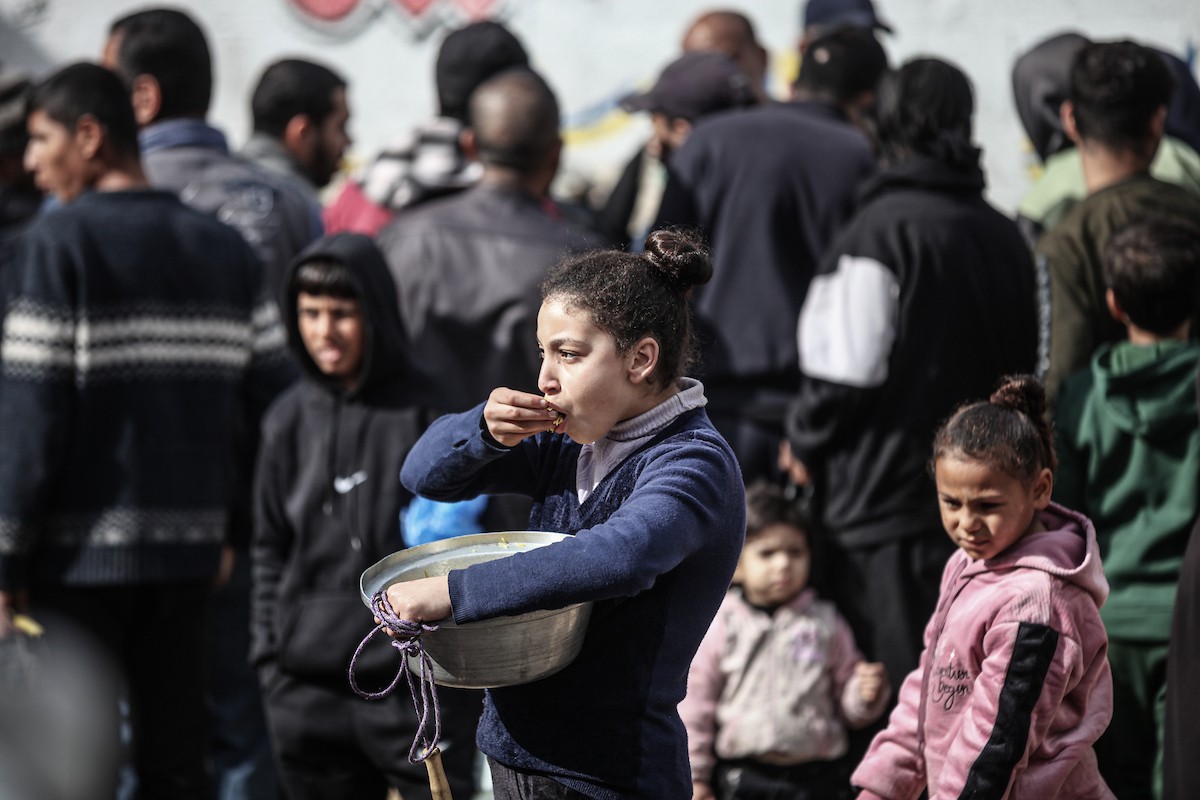 أطفال فلسطينيون ينتظرون وجبة ساخنة، توزعها إحدى المنظمات الخيرية، في ظل استمرار أزمة الغذاء بسبب محدودية المساعدات الإنسانية في مخيم النصيرات للاجئين وسط قطاع غزة، في 10 يناير/كانون الثاني 2026. صورة: معز صالحي