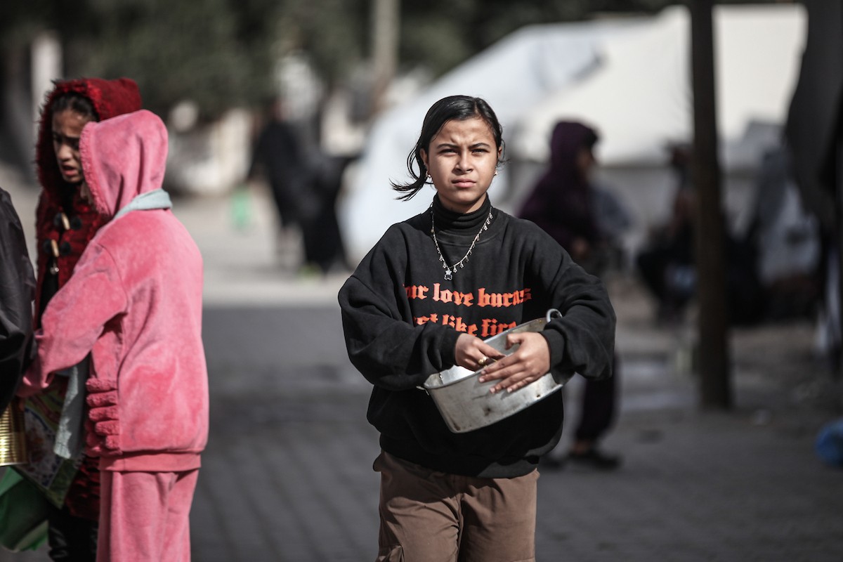 أطفال فلسطينيون ينتظرون وجبة ساخنة، توزعها إحدى المنظمات الخيرية، في ظل استمرار أزمة الغذاء بسبب محدودية المساعدات الإنسانية في مخيم النصيرات للاجئين وسط قطاع غزة، في 10 يناير/كانون الثاني 2026. صورة: معز صالحي