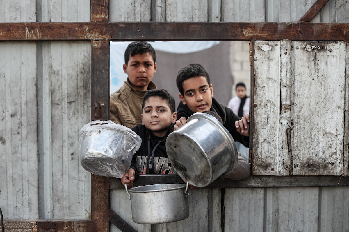 تلقى فلسطينيون، بينهم أطفال، وجبات ساخنة وزعتها إحدى الجمعيات الخيرية في مخيم النصيرات للاجئين، وسط نقص حاد في الغذاء ناجم عن الهجمات الإسرائيلية المستمرة وتدهور الأوضاع الإنسانية. النصيرات، وسط قطاع غزة. 26 يناير/كانون الثاني 2026. تصوير: معز صالحي