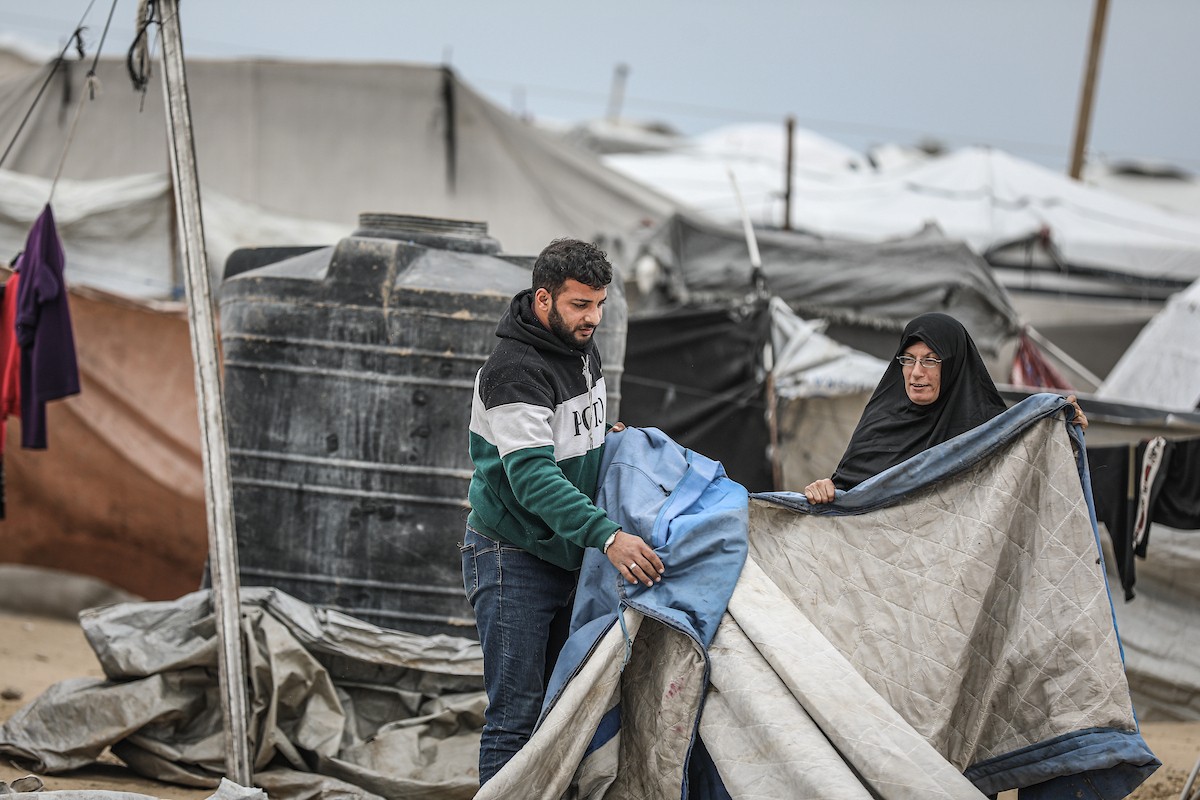 يتفقد فلسطينيون نازحون خيامهم بعد أن تضررت بشدة جراء عاصفة هوائية قوية ضربت مخيمًا للنازحين وسط قطاع غزة. 22 يناير/كانون الثاني 2026. تصوير: رمزي أبو عامر
