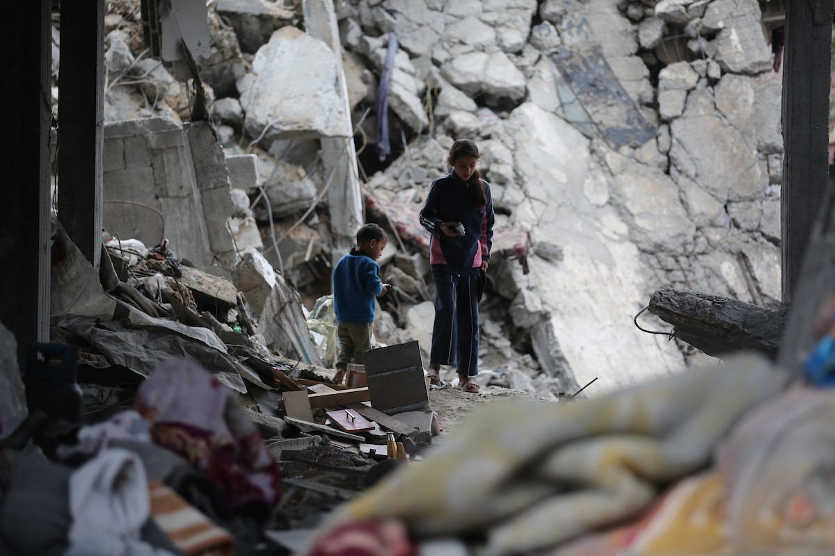 يبحث فلسطينيون عن ممتلكاتهم بين الأنقاض بعد أن دمرت غارات جوية إسرائيلية مبنى في مخيم البريج للاجئين وسط قطاع غزة. دمر الهجوم المبنى بالكامل وألحق أضرارًا بالمنشآت المحيطة به، 9 يناير/كانون الثاني 2026. صورة: معز صالحي