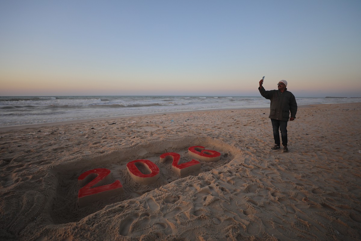 فلسطينيون يودعون عام 2025 بكتابة 2026 على رمال شاطئ غزة، 31 ديسمبركانون الأول 2025. صورة عمر أشتوي