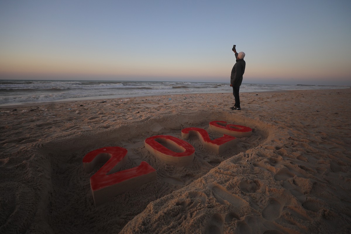 فلسطينيون يودعون عام 2025 بكتابة 2026 على رمال شاطئ غزة، 31 ديسمبركانون الأول 2025. صورة عمر أشتوي