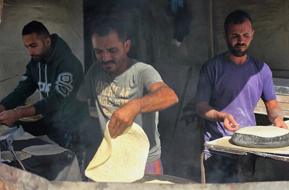 الفلسطيني محمد قحمان يعيد افتتاح مخبز تقليدي وسط أنقاض مدينة حمد غرب خان يونس، ويعمل جنباً إلى جنب مع أبنائه وصهره، وجميعهم من مبتوري الأطراف، 21 يناير/كانون الثاني 2026  . صورة: طارق محمد