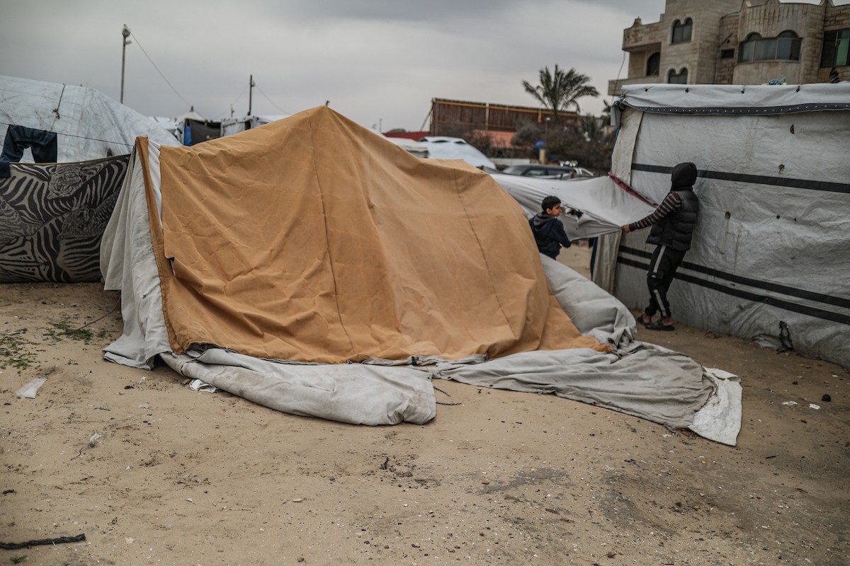 يتفقد فلسطينيون نازحون خيامهم بعد أن تضررت بشدة جراء عاصفة هوائية قوية ضربت مخيمًا للنازحين وسط قطاع غزة. 22 يناير/كانون الثاني 2026. تصوير: رمزي أبو عامر