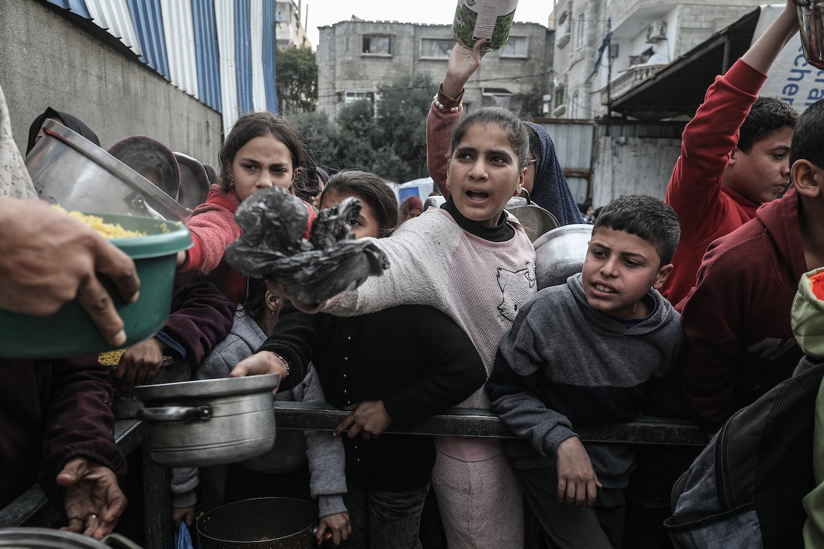 أطفال فلسطينيون ينتظرون وجبة ساخنة، توزعها إحدى المنظمات الخيرية، في ظل استمرار أزمة الغذاء بسبب محدودية المساعدات الإنسانية في مخيم النصيرات للاجئين وسط قطاع غزة، في 10 يناير/كانون الثاني 2026. صورة: معز صالحي