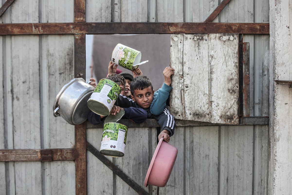 أطفال فلسطينيون ينتظرون وجبة ساخنة، توزعها إحدى المنظمات الخيرية، في ظل استمرار أزمة الغذاء بسبب محدودية المساعدات الإنسانية في مخيم النصيرات للاجئين وسط قطاع غزة، في 10 يناير/كانون الثاني 2026. صورة: معز صالحي