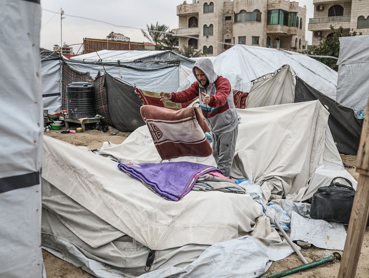 يتفقد فلسطينيون نازحون خيامهم بعد أن تضررت بشدة جراء عاصفة هوائية قوية ضربت مخيمًا للنازحين وسط قطاع غزة. 22 يناير/كانون الثاني 2026. تصوير: رمزي أبو عامر