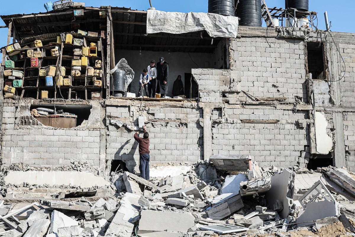 فلسطينيون يتفقدون منزلاً (تضرر سابقاً جراء غارة جوية إسرائيلية) انهار على سكانه، ما أسفر عن وفاة رجل ونجله الصغير في مخيم المغازي للاجئين وسط قطاع غزة، 5 يناير/كانون الثاني 2026. صورة: رمزي أبو عامر