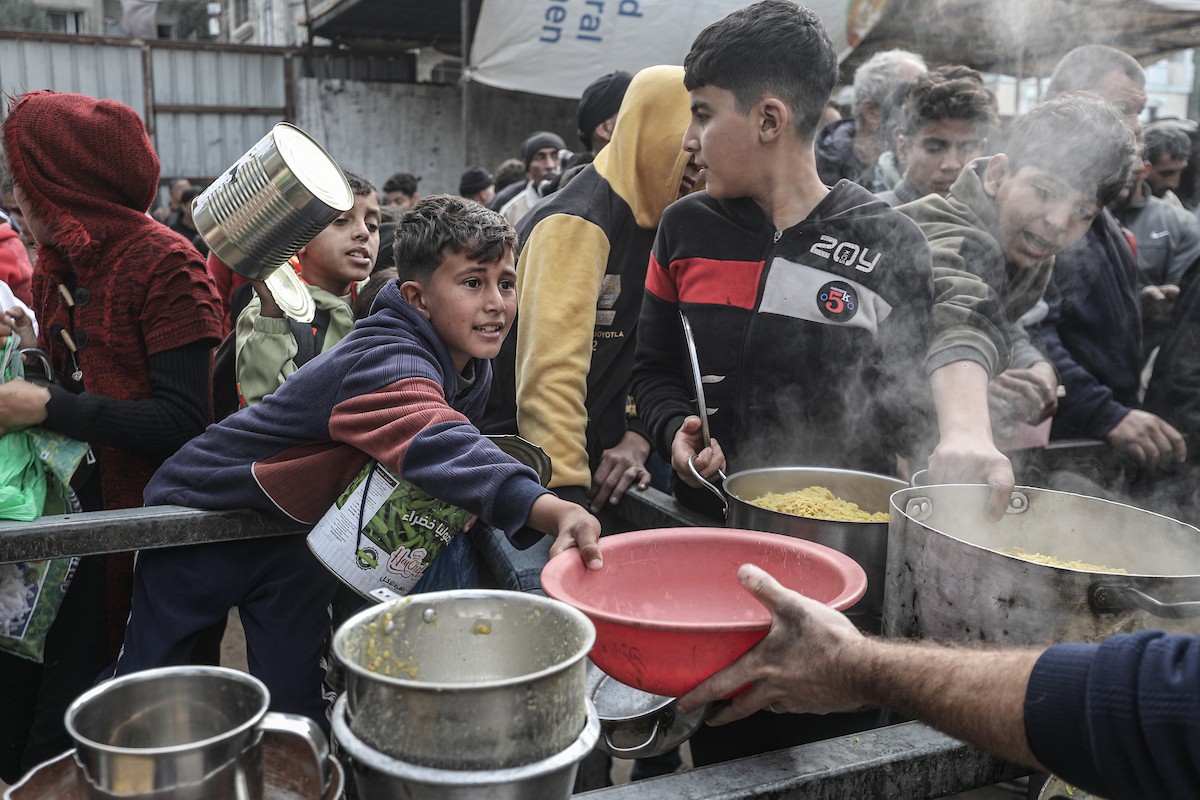 أطفال فلسطينيون ينتظرون وجبة ساخنة، توزعها إحدى المنظمات الخيرية، في ظل استمرار أزمة الغذاء بسبب محدودية المساعدات الإنسانية في مخيم النصيرات للاجئين وسط قطاع غزة، في 10 يناير/كانون الثاني 2026. صورة: معز صالحي