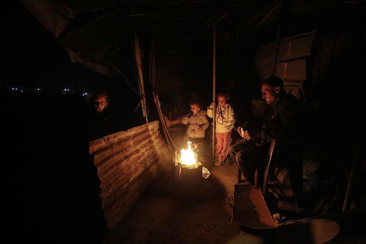 عائلات تعيش في خيام مؤقتة وسط الأنقاض تشعل نيرانًا للتدفئة في جباليا، شمال قطاع غزة، في 12 يناير/كانون الثاني 2026. ويكافح الفلسطينيون الذين دُمرت منازلهم في هجمات إسرائيلية من أجل البقاء في ظل ظروف شتوية قاسية وبرد قارس. صورة: عمر أشتوي