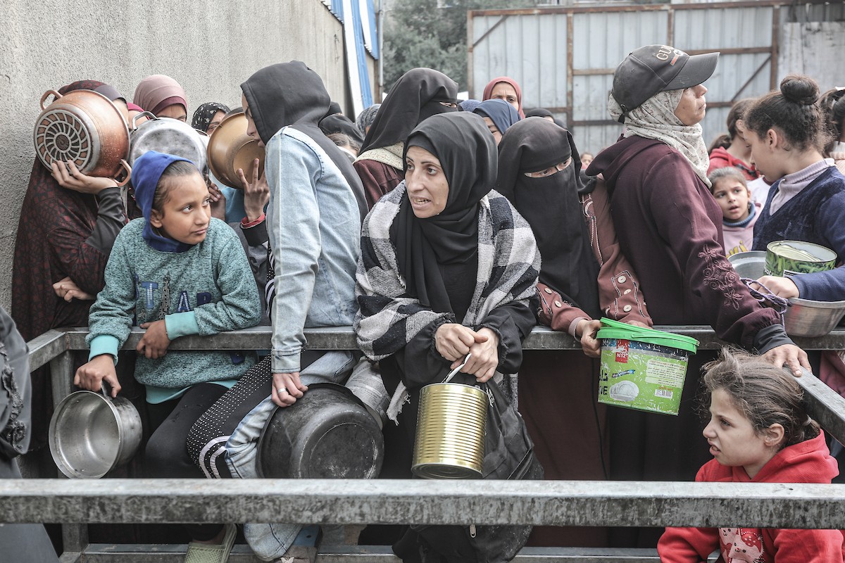 أطفال فلسطينيون ينتظرون وجبة ساخنة، توزعها إحدى المنظمات الخيرية، في ظل استمرار أزمة الغذاء بسبب محدودية المساعدات الإنسانية في مخيم النصيرات للاجئين وسط قطاع غزة، في 10 يناير/كانون الثاني 2026. صورة: معز صالحي