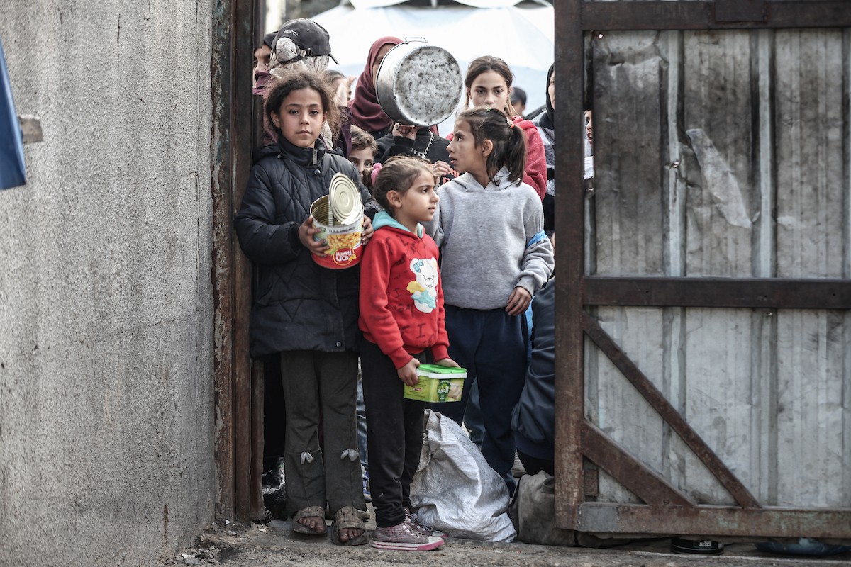 أطفال فلسطينيون ينتظرون وجبة ساخنة، توزعها إحدى المنظمات الخيرية، في ظل استمرار أزمة الغذاء بسبب محدودية المساعدات الإنسانية في مخيم النصيرات للاجئين وسط قطاع غزة، في 10 يناير/كانون الثاني 2026. صورة: معز صالحي