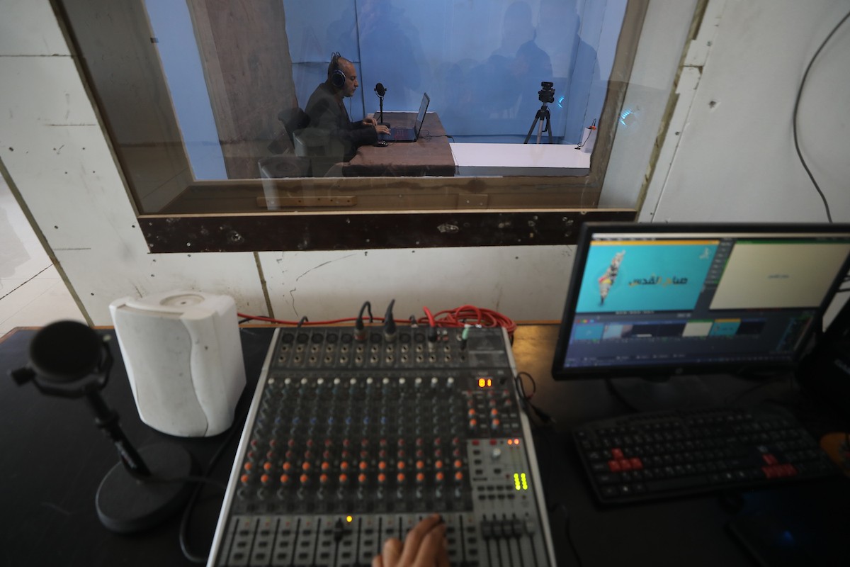 مذيع راديو فلسطيني يبث عبر الإنترنت من استوديوهات إذاعة صوت القدس في غزة، 24 يناير/كانون الثاني 2026. عادت الإذاعة إلى البث بعد توقف دام عامين بسبب الحرب، معتمدةً على معدات بسيطة للتواصل مع الجمهور المحلي ونقل الأخبار عن الأوضاع الإنسانية في القطاع. صورة: عمر أشتوي
