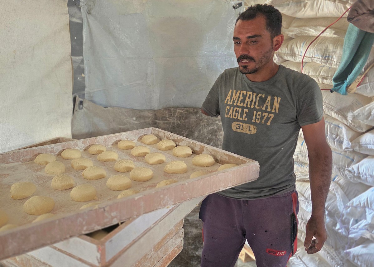 الفلسطيني محمد قحمان يعيد افتتاح مخبز تقليدي وسط أنقاض مدينة حمد غرب خان يونس، ويعمل جنباً إلى جنب مع أبنائه وصهره، وجميعهم من مبتوري الأطراف، 21 يناير/كانون الثاني 2026  . صورة: طارق محمد