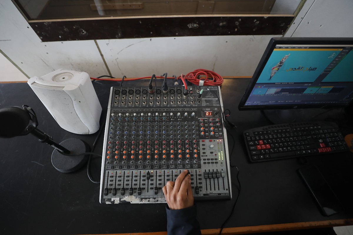 مذيع راديو فلسطيني يبث عبر الإنترنت من استوديوهات إذاعة صوت القدس في غزة، 24 يناير/كانون الثاني 2026. عادت الإذاعة إلى البث بعد توقف دام عامين بسبب الحرب، معتمدةً على معدات بسيطة للتواصل مع الجمهور المحلي ونقل الأخبار عن الأوضاع الإنسانية في القطاع. صورة: عمر أشتوي