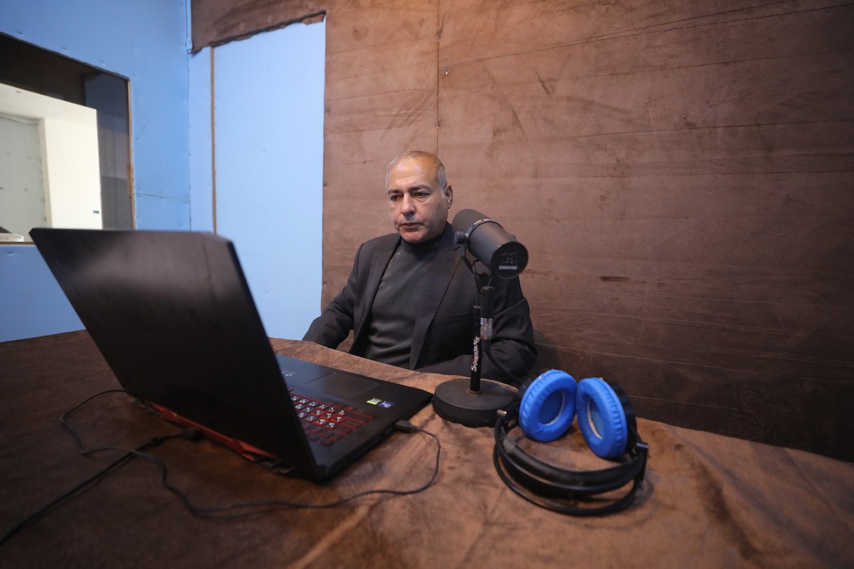 مذيع راديو فلسطيني يبث عبر الإنترنت من استوديوهات إذاعة صوت القدس في غزة، 24 يناير/كانون الثاني 2026. عادت الإذاعة إلى البث بعد توقف دام عامين بسبب الحرب، معتمدةً على معدات بسيطة للتواصل مع الجمهور المحلي ونقل الأخبار عن الأوضاع الإنسانية في القطاع. صورة: عمر أشتوي