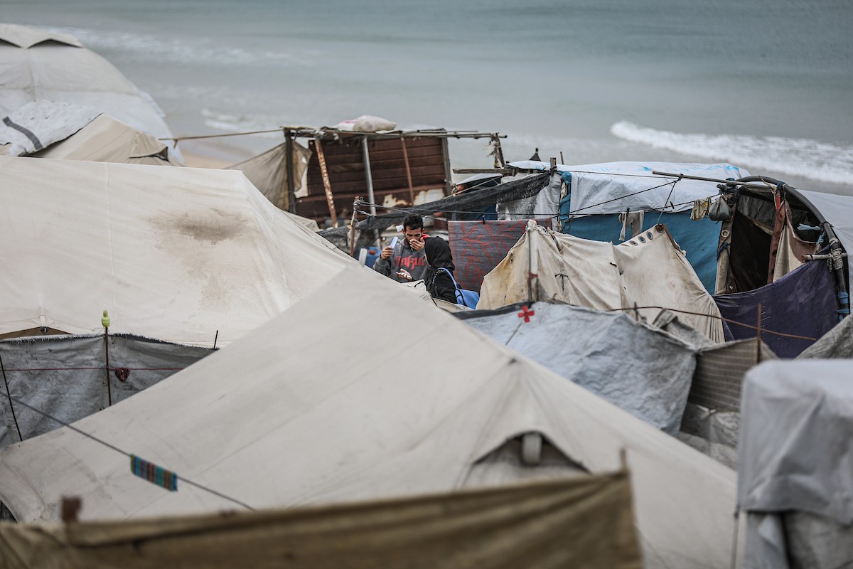 يتفقد فلسطينيون نازحون خيامهم بعد أن تضررت بشدة جراء عاصفة هوائية قوية ضربت مخيمًا للنازحين وسط قطاع غزة. 22 يناير/كانون الثاني 2026. تصوير: رمزي أبو عامر