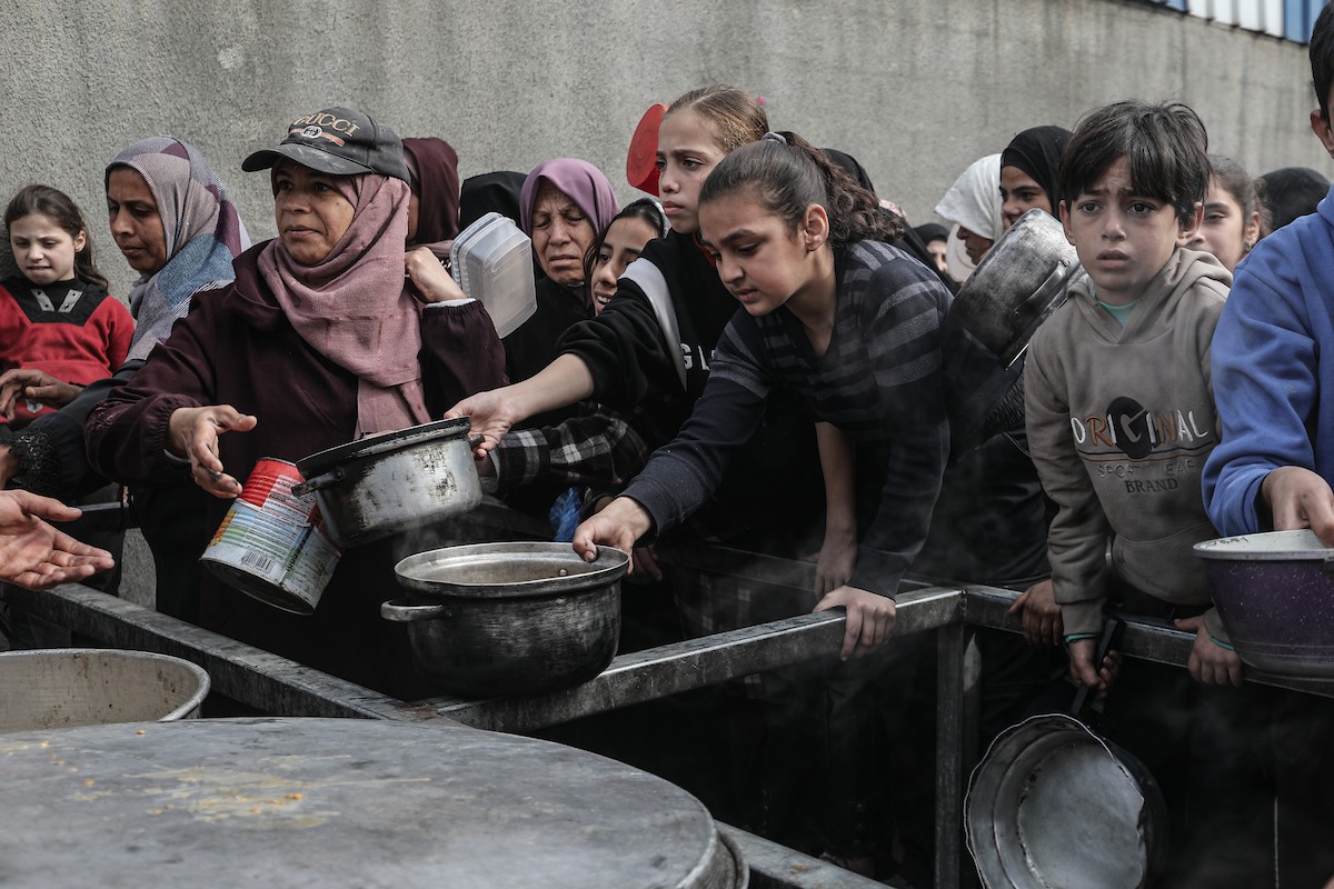 تلقى فلسطينيون، بينهم أطفال، وجبات ساخنة وزعتها إحدى الجمعيات الخيرية في مخيم النصيرات للاجئين، وسط نقص حاد في الغذاء ناجم عن الهجمات الإسرائيلية المستمرة وتدهور الأوضاع الإنسانية. النصيرات، وسط قطاع غزة. 26 يناير/كانون الثاني 2026. تصوير: معز صالحي