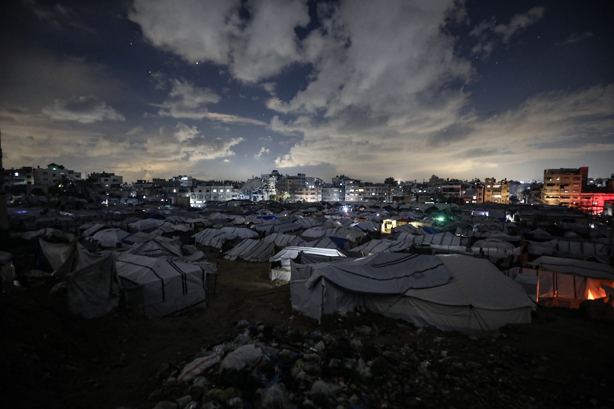 يسير فلسطينيون في أحد شوارع مدينة غزة، بينما يكافح النازحون في خيامهم لمواجهة الظلام، يتدفؤون ويطهون طعامهم بالحطب، محرومين حتى من أبسط مقومات الحياة، 19 يناير/كانون الثاني 2026. صورة: عمر أشتوي