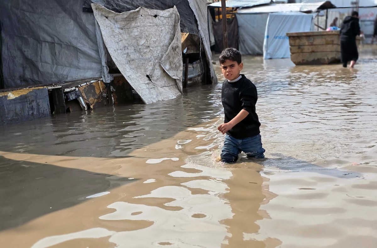 يحاول الفلسطينيون التنقل بعد أن غمرت مياه الأمطار الشوارع وخيام النازحين في خان يونس، جنوب قطاع غزة، في 24 فبراير/شباط 2026. وقد دُمرت البنية التحتية في قطاع غزة على نطاق واسع جراء الحرب والهجمات الإسرائيلية. (صورة: طارق محمد)