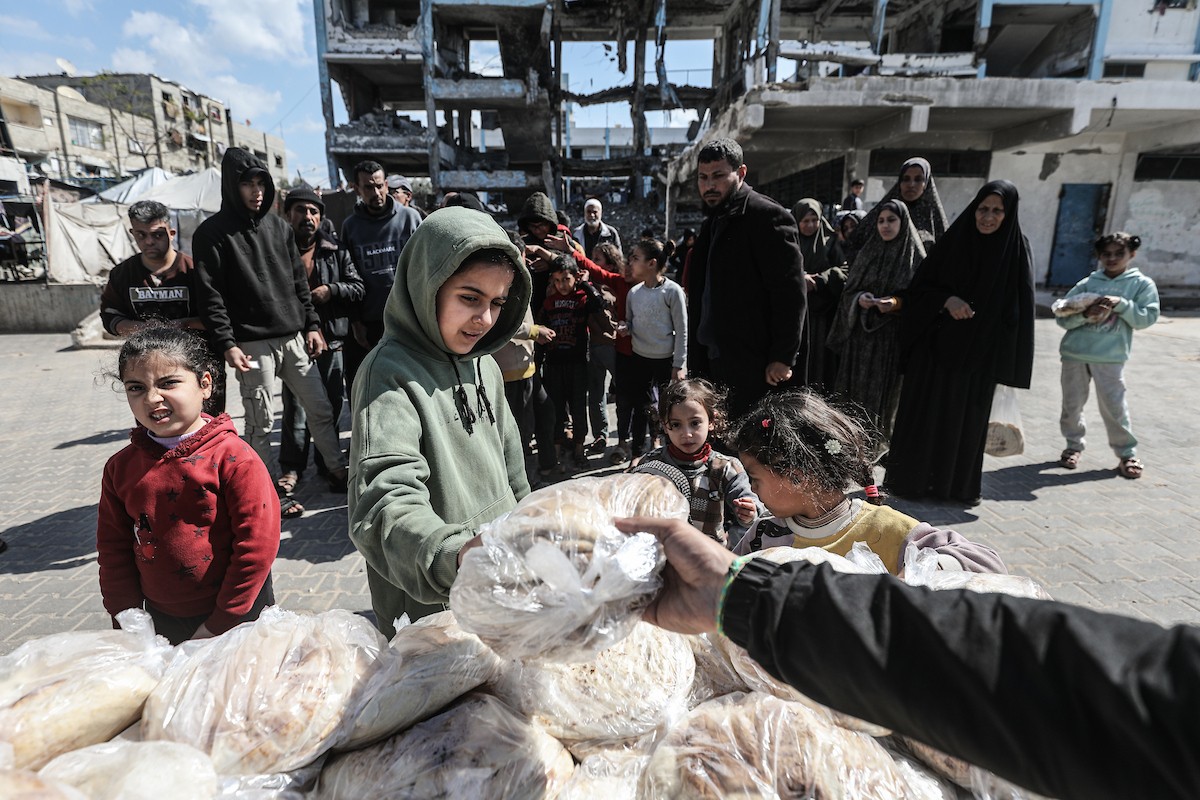 نساء فلسطينيات، زوجات شهداء الحرب، يُجهّزن الخبز لتوزيعه على العائلات النازحة والمحتاجة في مخيم البريج للاجئين وسط قطاع غزة خلال شهر رمضان، في مشهد يُجسّد روح التضامن والصمود في ظلّ الظروف الإنسانية الصعبة، فبراير/شباط 2026. تصوير: معز صالحي