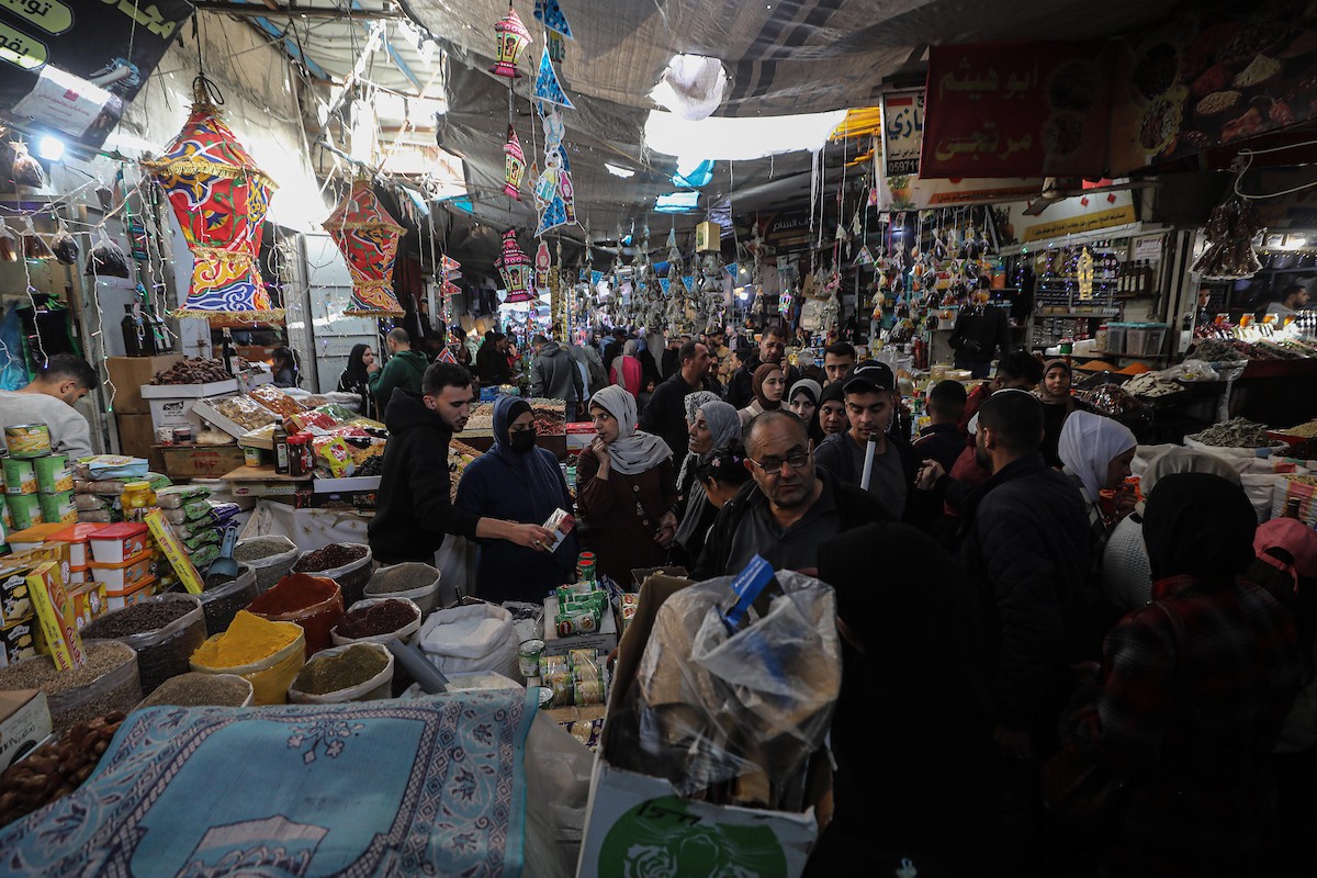 يتسوق الفلسطينيون في أول ليلة من شهر رمضان المبارك في سوق الزاوية، الواقع في قلب مدينة غزة والذي تضرر بشدة جراء الحرب الإسرائيلية. يعرض الباعة بضائعهم على أكشاك مزينة بالفوانيس والأضواء وأطعمة رمضان. مدينة غزة، 17 فبراير/شباط 2026. تصوير: عمر أشتوي