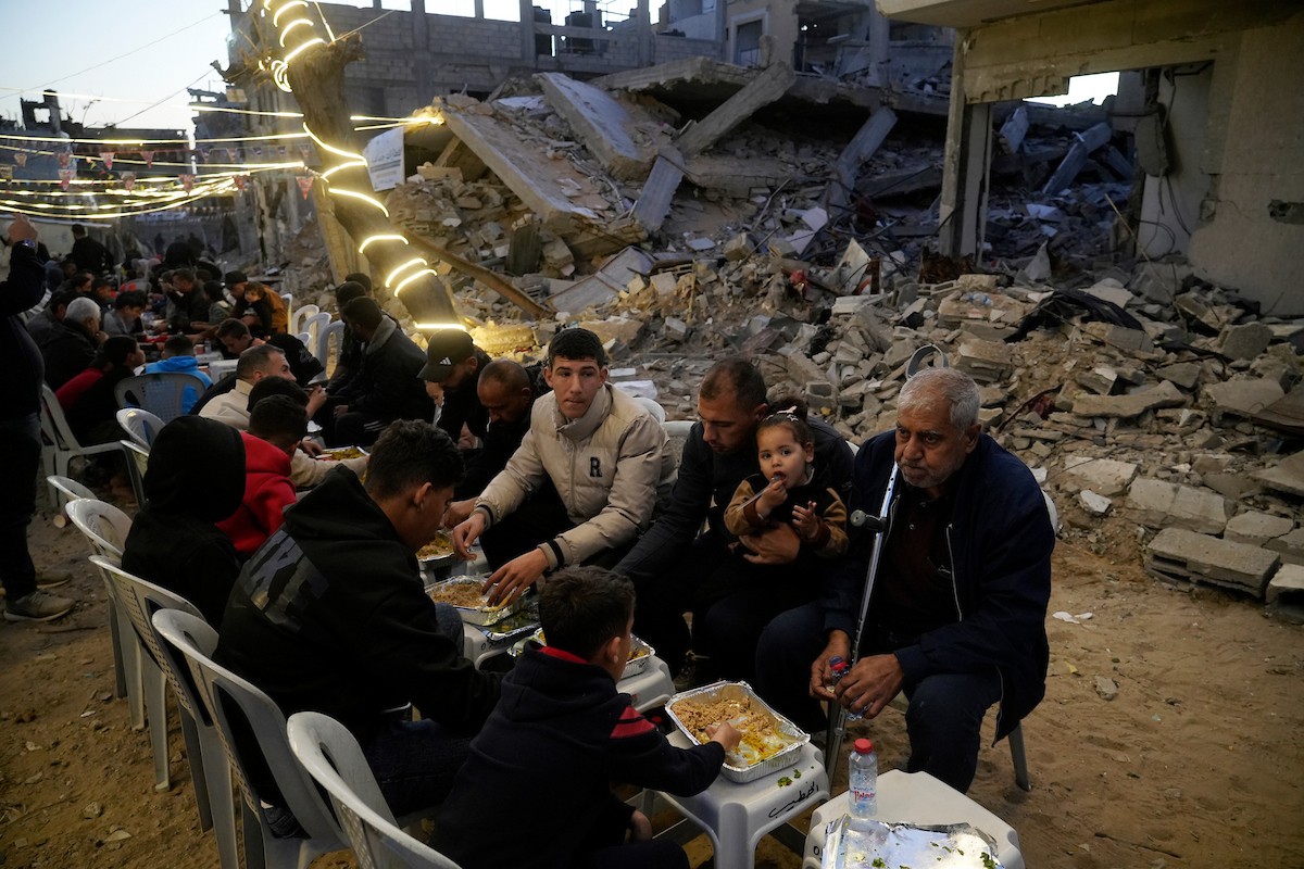 يتجمع الفلسطينيون بين المنازل المدمرة لتناول وجبة الإفطار معًا خلال شهر رمضان المبارك في شمال قطاع غزة، 22 فبراير/شباط 2026. صورة: عمر أشتوي