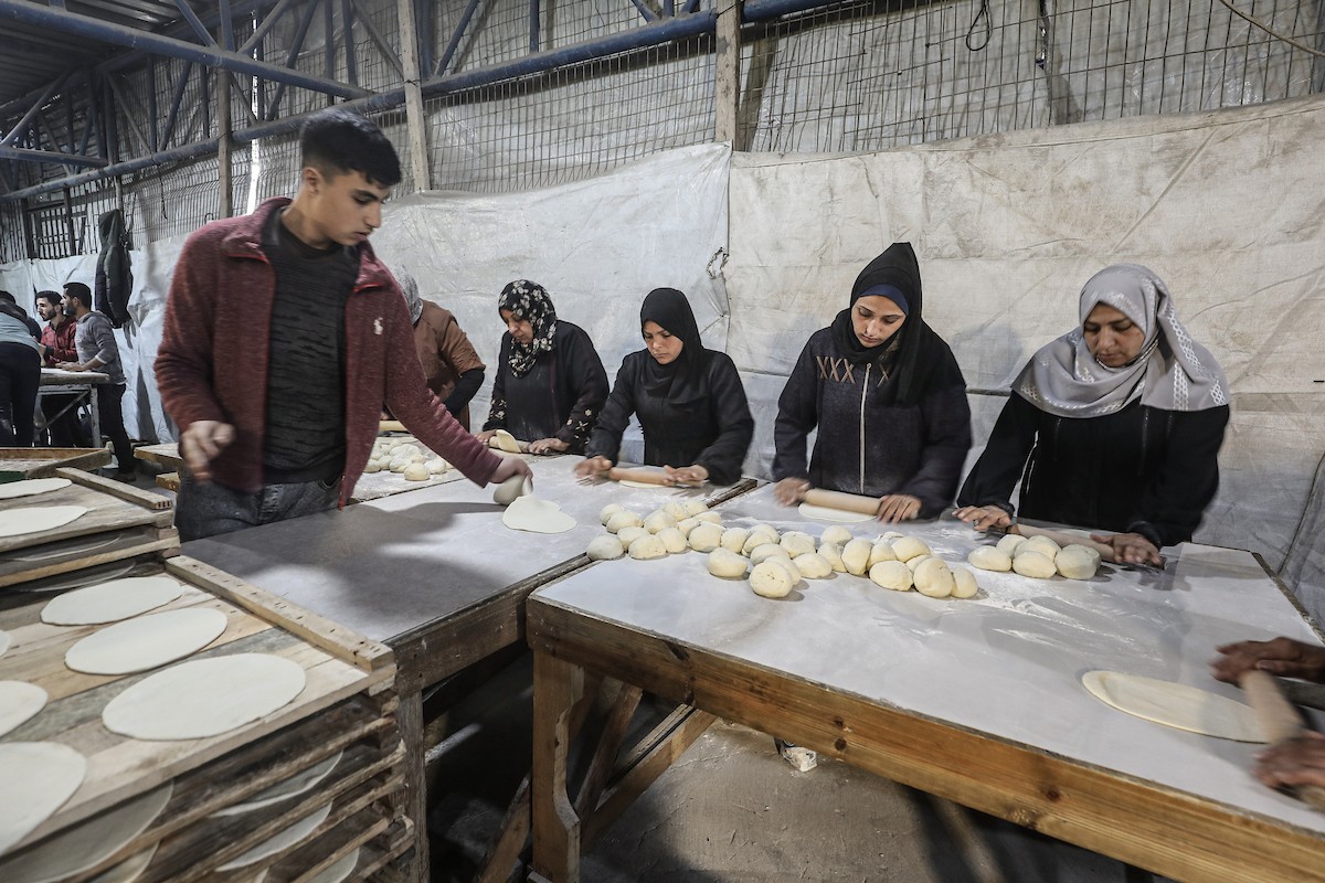 نساء فلسطينيات، زوجات شهداء الحرب، يُجهّزن الخبز لتوزيعه على العائلات النازحة والمحتاجة في مخيم البريج للاجئين وسط قطاع غزة خلال شهر رمضان، في مشهد يُجسّد روح التضامن والصمود في ظلّ الظروف الإنسانية الصعبة، فبراير/شباط 2026. تصوير: معز صالحي