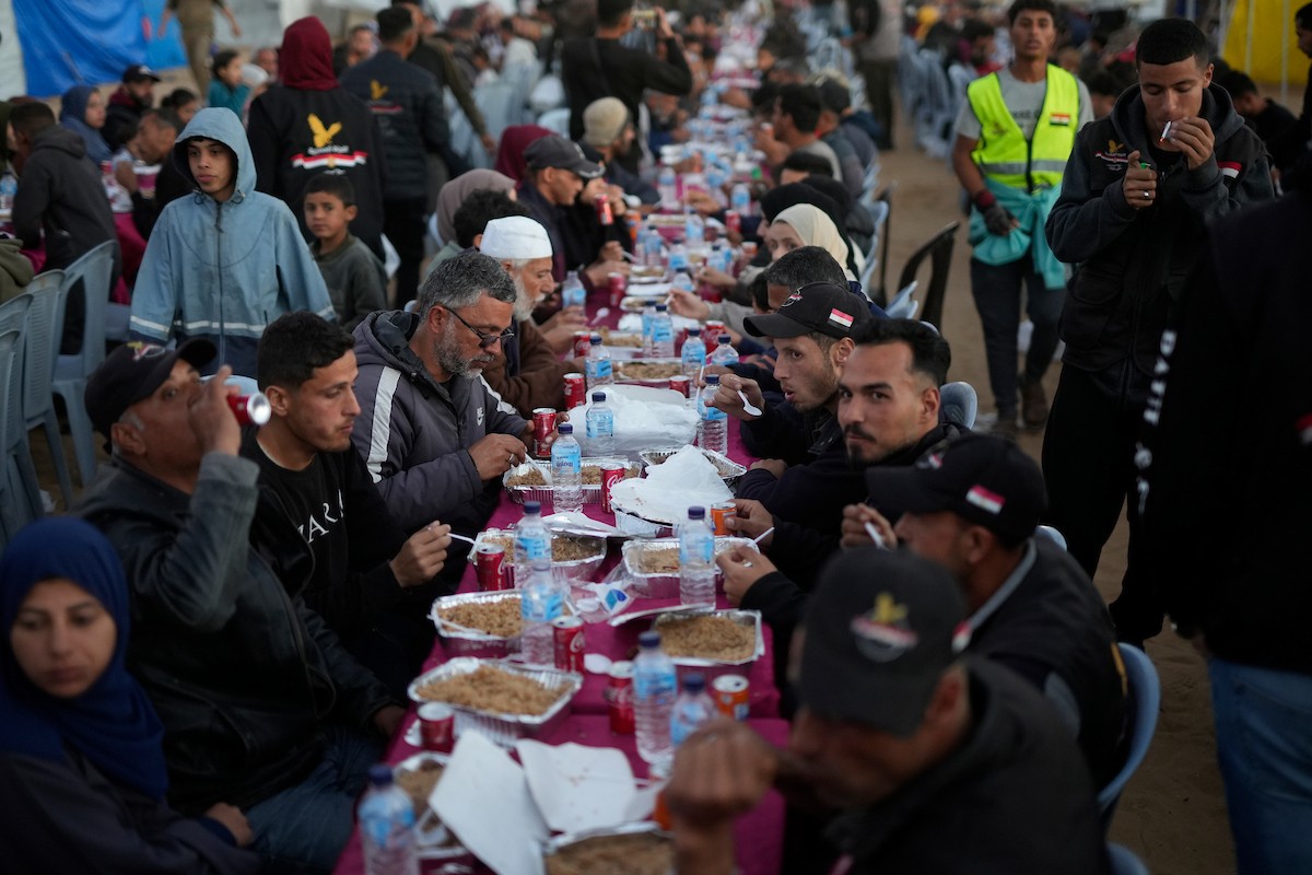 يتجمع فلسطينيون نازحون لتناول وجبة الإفطار، وهي وجبة كسر الصيام، خلال شهر رمضان المبارك في مخيم خيام يؤويهم، بحي الزهراء وسط قطاع غزة، يوم السبت 21 فبراير/شباط 2026. تصوير: عمر أشتوي