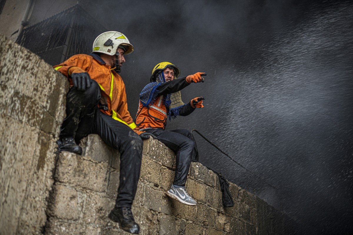 طواقم الدفاع المدني ومتطوعون من المواطنين أثناء محاولة إخماد حريق اندلع في مستودع تابع لمنظمة إغاثة في حي الرمال، غرب مدينة غزة، في 13 فبراير/شباط 2026. صورة: عمر أشتوي