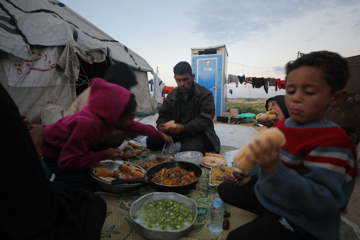 عائلة فلسطينية كفيفة تتناول وجبة الإفطار خارج خيمتها في مخيم بوسط قطاع غزة خلال شهر رمضان