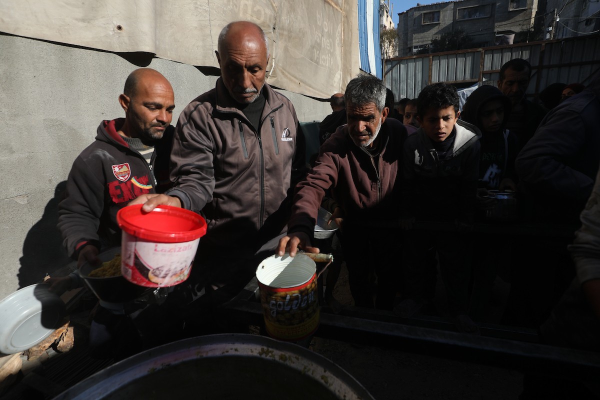 يتجمع فلسطينيون لتناول وجبة ساخنة وزعتها إحدى الجمعيات الخيرية، وسط أزمة غذائية مستمرة بسبب محدودية المساعدات الإنسانية خلال شهر رمضان في مخيم النصيرات للاجئين وسط قطاع غزة. ٢٣ فبرايرشباط ٢٠٢٦. تصوير معز صالحي