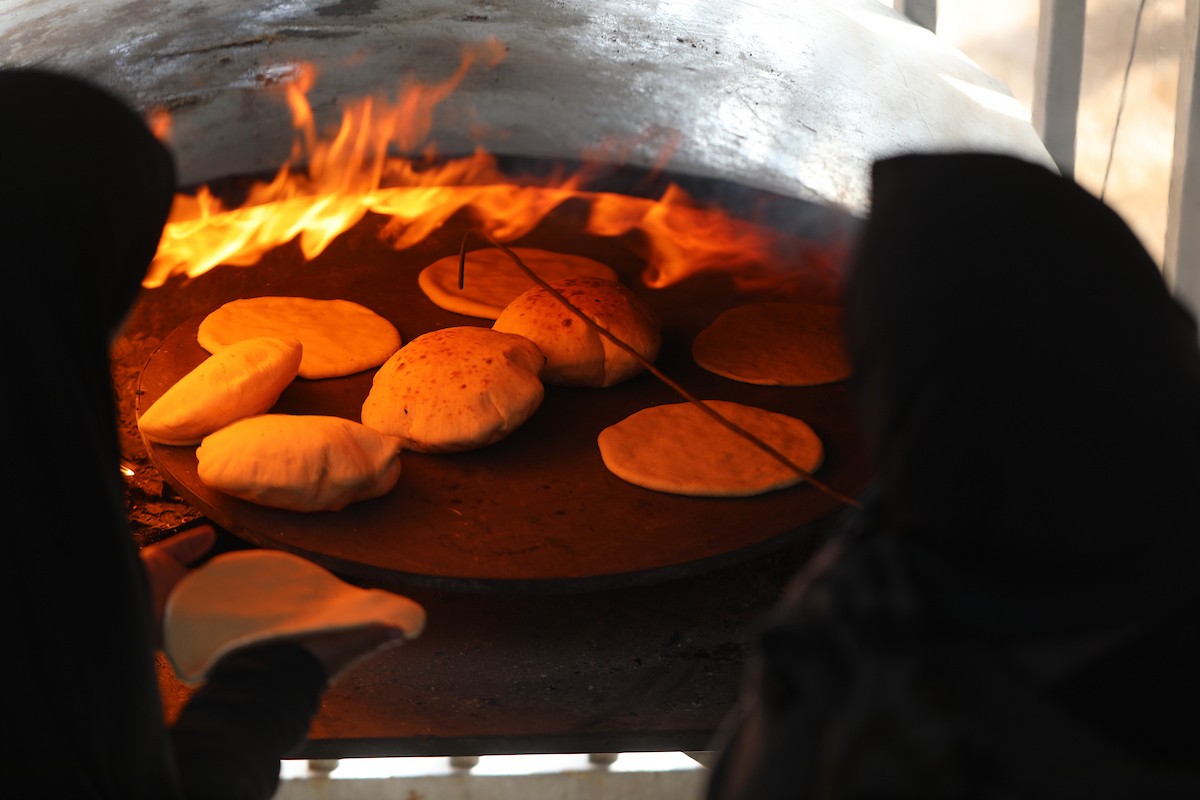 مجموعة من النساء يعملن داخل مخبز أُنشئ في مخيم اليرموك للاجئين بمدينة غزة، ضمن مبادرة إنسانية بالشراكة مع اللجنة الدولية للصليب الأحمر. تهدف المبادرة إلى تخفيف الأعباء المعيشية عن النساء النازحات، لا سيما خلال شهر رمضان. مدينة غزة، 25 فبراير/شباط 2026. تصوير: عمر أشتوي