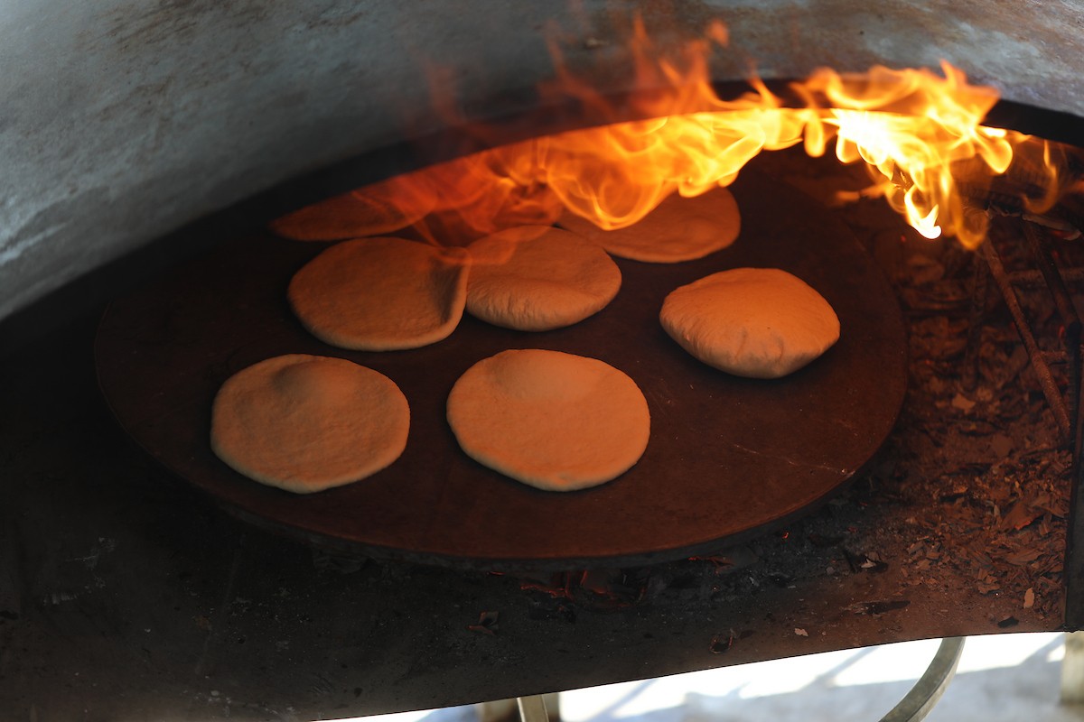 مجموعة من النساء يعملن داخل مخبز أُنشئ في مخيم اليرموك للاجئين بمدينة غزة، ضمن مبادرة إنسانية بالشراكة مع اللجنة الدولية للصليب الأحمر. تهدف المبادرة إلى تخفيف الأعباء المعيشية عن النساء النازحات، لا سيما خلال شهر رمضان. مدينة غزة، 25 فبراير/شباط 2026. تصوير: عمر أشتوي