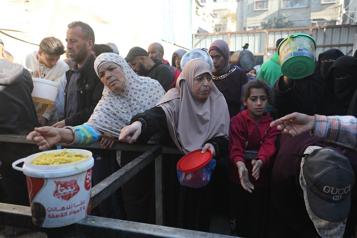 يتجمع فلسطينيون لتناول وجبة ساخنة وزعتها إحدى الجمعيات الخيرية، وسط أزمة غذائية مستمرة بسبب محدودية المساعدات الإنسانية خلال شهر رمضان في مخيم النصيرات للاجئين وسط قطاع غزة. ٢٣ فبرايرشباط ٢٠٢٦. تصوير معز صالحي