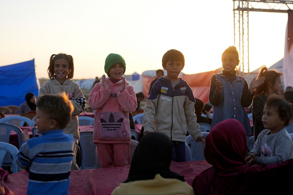 يتجمع فلسطينيون نازحون لتناول وجبة الإفطار، وهي وجبة كسر الصيام، خلال شهر رمضان المبارك في مخيم خيام يؤويهم، بحي الزهراء وسط قطاع غزة، يوم السبت 21 فبراير/شباط 2026. تصوير: عمر أشتوي