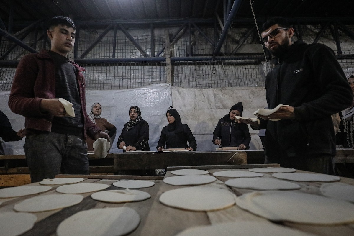 نساء فلسطينيات، زوجات شهداء الحرب، يُجهّزن الخبز لتوزيعه على العائلات النازحة والمحتاجة في مخيم البريج للاجئين وسط قطاع غزة خلال شهر رمضان، في مشهد يُجسّد روح التضامن والصمود في ظلّ الظروف الإنسانية الصعبة، فبراير/شباط 2026. تصوير: معز صالحي