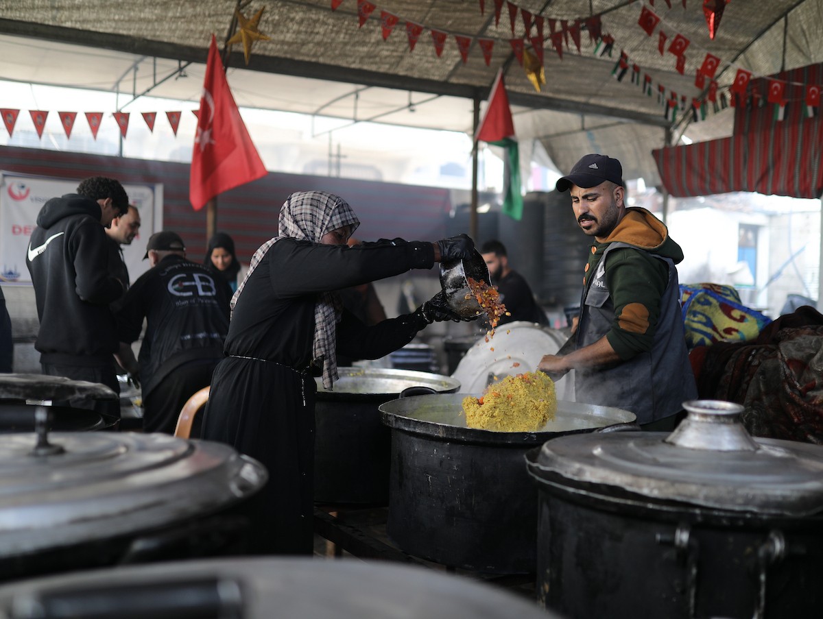 يتجمع فلسطينيون نازحون لتناول وجبة إفطارهم الرمضانية في مطبخ خيري بمخيم النصيرات للاجئين وسط قطاع غزة، في 24 فبراير/شباط 2026. ويواجه النازحون ظروفًا معيشية قاسية نتيجة انعدام الدخل ونقص المساعدات الإنسانية. (صورة: رمزي أبو عامر / apaimages)