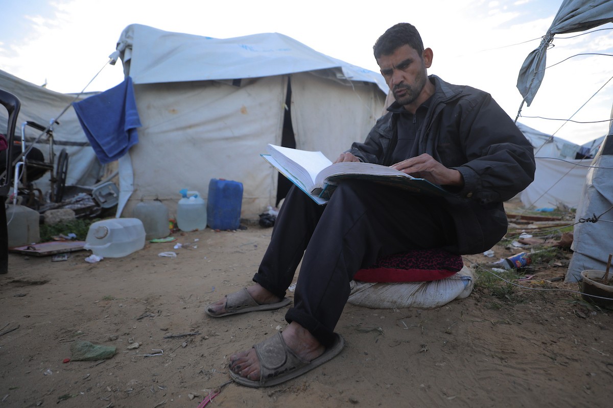 عائلة فلسطينية كفيفة تتناول وجبة الإفطار خارج خيمتها في مخيم بوسط قطاع غزة خلال شهر رمضان