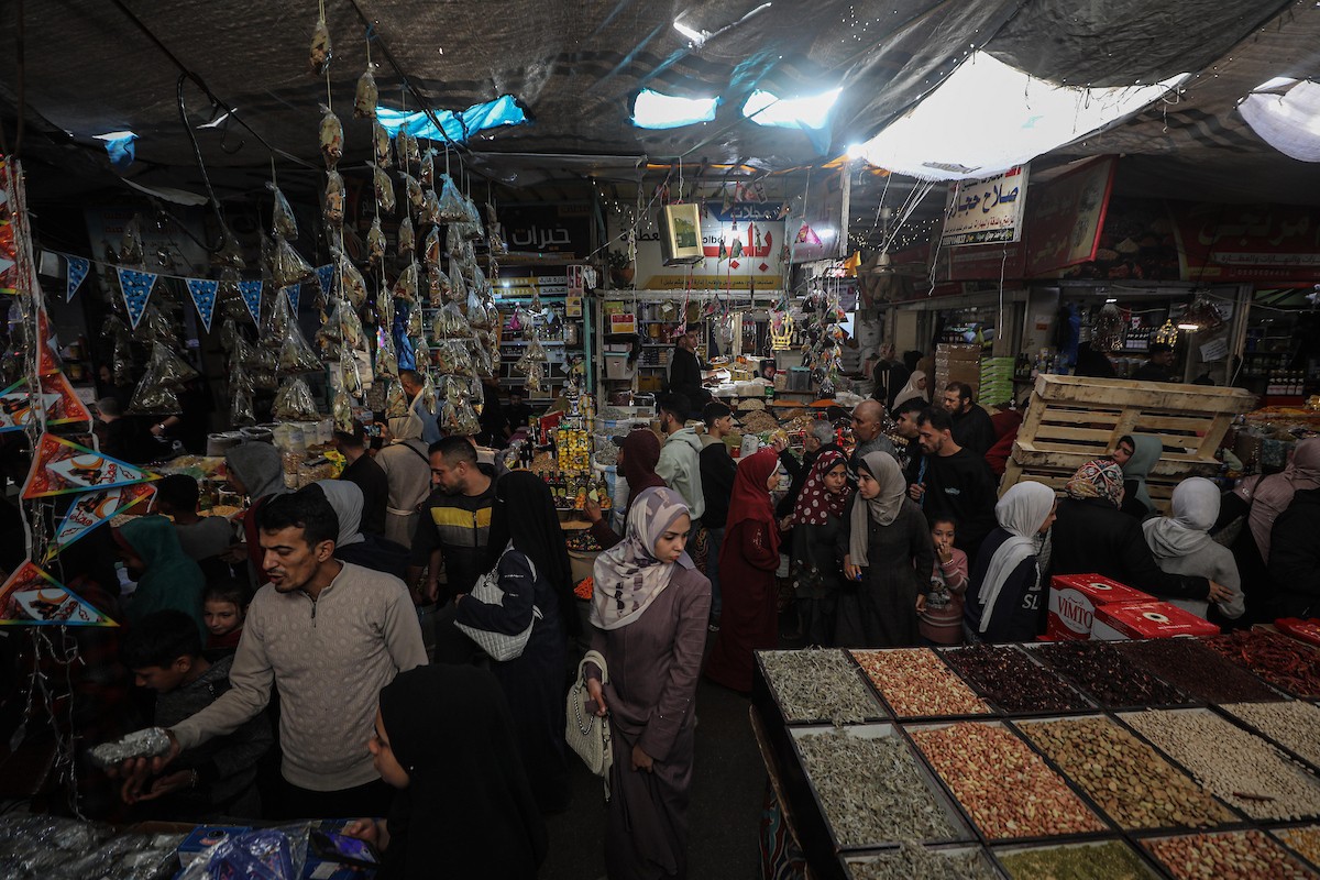 يتسوق الفلسطينيون في أول ليلة من شهر رمضان المبارك في سوق الزاوية، الواقع في قلب مدينة غزة والذي تضرر بشدة جراء الحرب الإسرائيلية. يعرض الباعة بضائعهم على أكشاك مزينة بالفوانيس والأضواء وأطعمة رمضان. مدينة غزة، 17 فبراير/شباط 2026. تصوير: عمر أشتوي